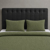 Olive green waffle-weave blanket and matching pillow covers on a bed.