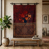 A large wall tapestry featuring a dark red upper section with a black cat and red/orange leaves, and a brown patterned lower section, hanging on a black rod in a styled room with a bench, plant, and books.