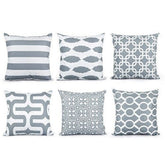 Six grey and white cushion covers with stripes and interlocking geometric patterns.
