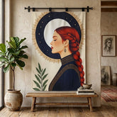 A vertical fabric wall tapestry hanging from a black rod in a rustic room. The tapestry features an illustration of a woman with a red braid in profile against a cream background with a starry dark blue crescent moon and gold decorative border.