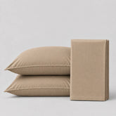 Light tan bedsheet and pillows on a light grey surface