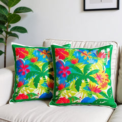 Colorful floral-patterned pillows on a white couch with a plant and framed picture in the background.