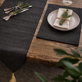 Close view of a black textured runner and matching placemat beneath a plate.