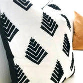 Close view of a cream cushion cover with raised black chevron motifs.