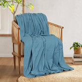 Teal textured blanket draped over a wooden armchair.