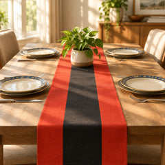 Red and black striped table runner on a wooden dining table set with plates.
