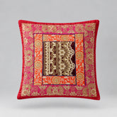 Red-bordered cushion cover with ornate pink and gold coloured floral bands and a dark patterned centre.