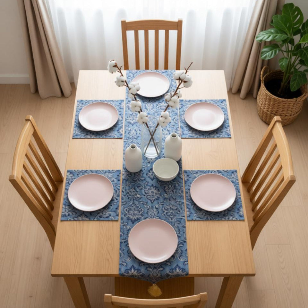 Dining table set with blue placemats, pink plates, and decorative vases.
