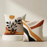Two decorative throw pillows with abstract geometric and botanical patterns in warm neutral tones, displayed on a white pedestal against a beige wall.