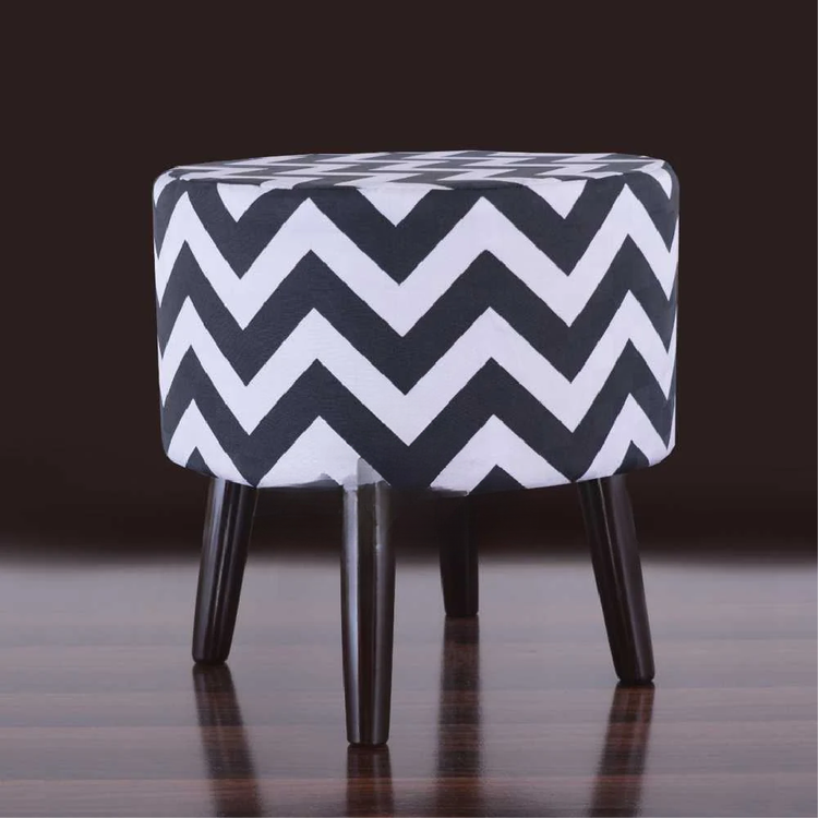 Black and white chevron ottoman against a dark background.
