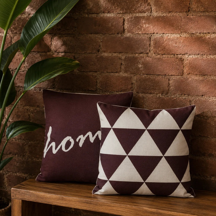 Two burgundy cushion covers with cream home lettering and a triangle pattern.