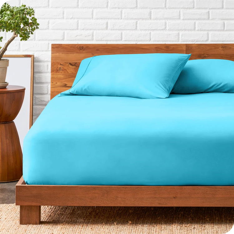 Peacock blue fitted sheet and matching pillowcases displayed on a bed.