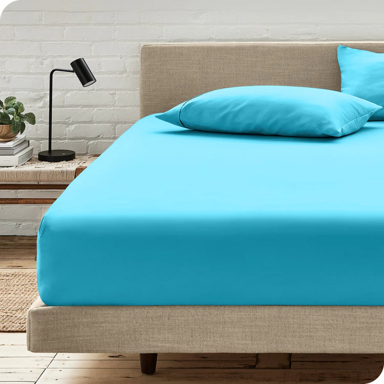 Peacock blue fitted sheet displayed on a bed with one matching pillow.