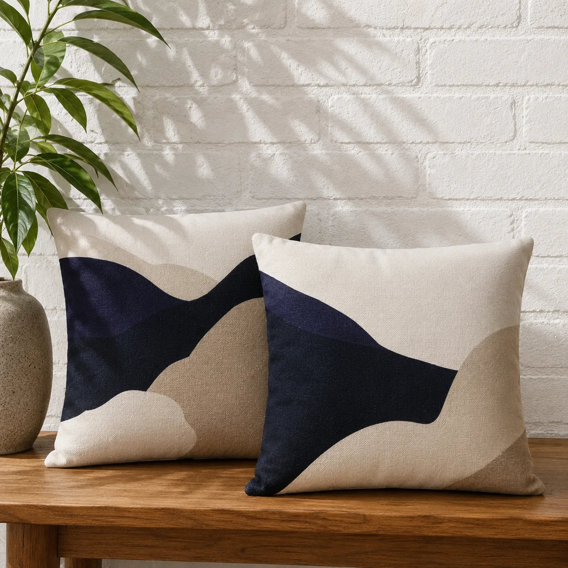 Two cushion covers with broad navy and cream curved shapes on a wooden bench