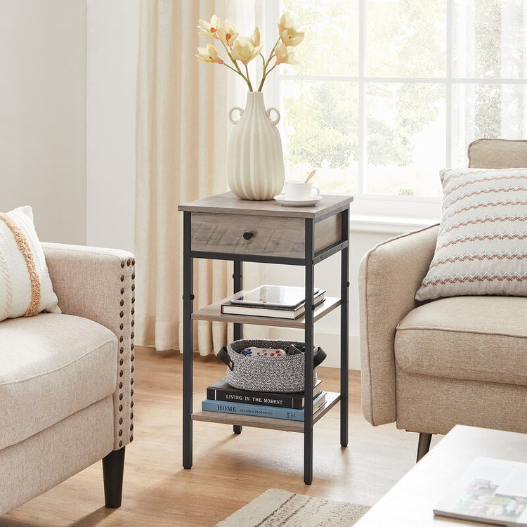 Gray-brown side table with drawer and two shelves between armchairs