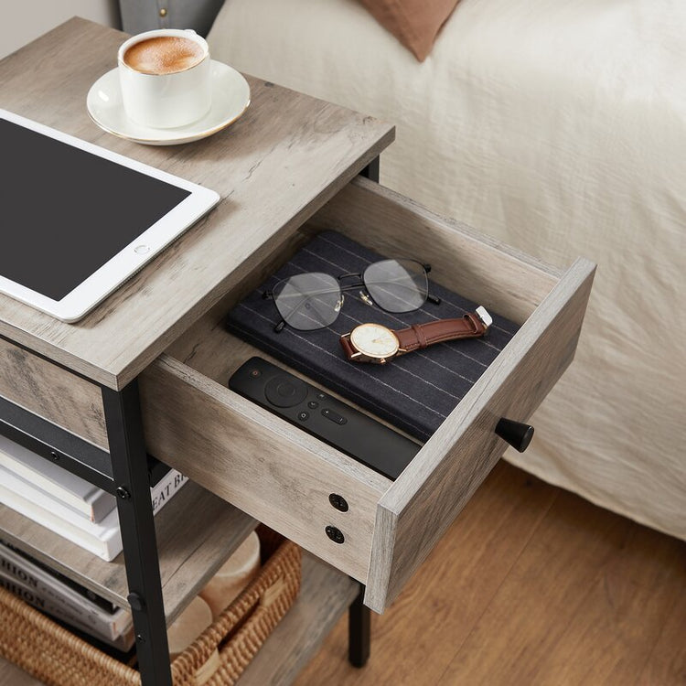 Close-up of an open side-table drawer holding a watch and notebook