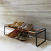 Low black shoe rack with wood-tone rails holding shoes