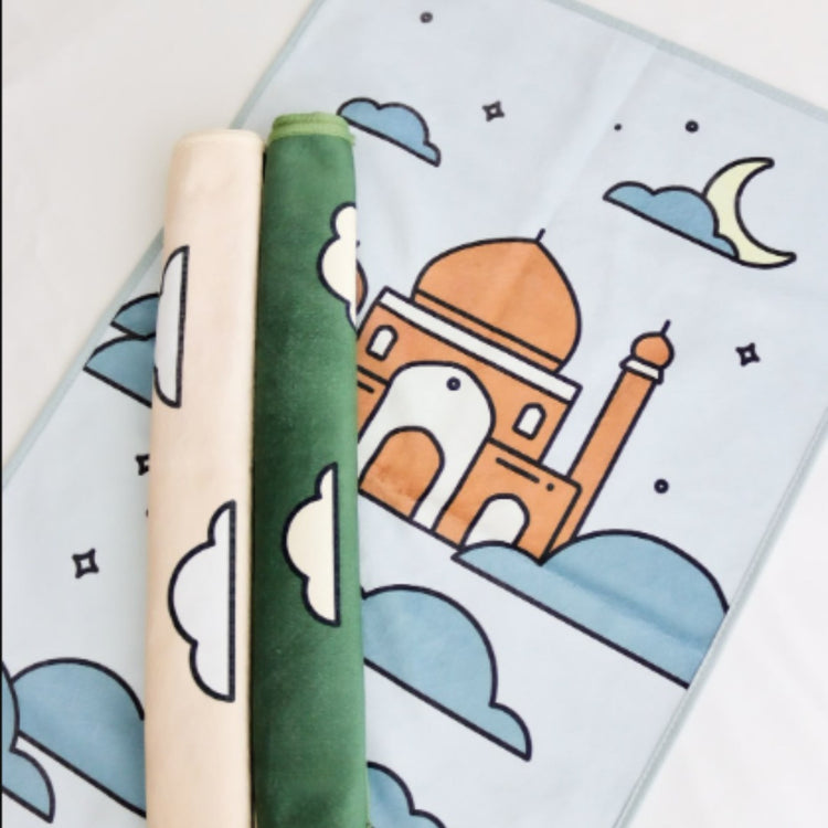 Children's prayer mat with a mosque, crescent moons and cloud illustrations.