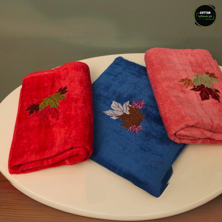 Three colourful towels in red, blue and pink with small decorative embroidered motifs.