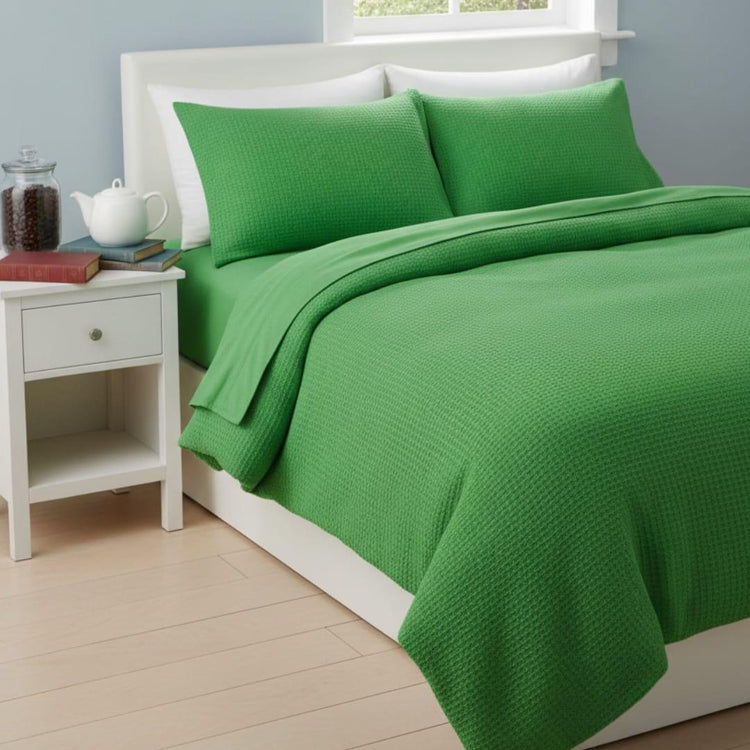 Bright green textured blanket with matching pillow covers on a bed.