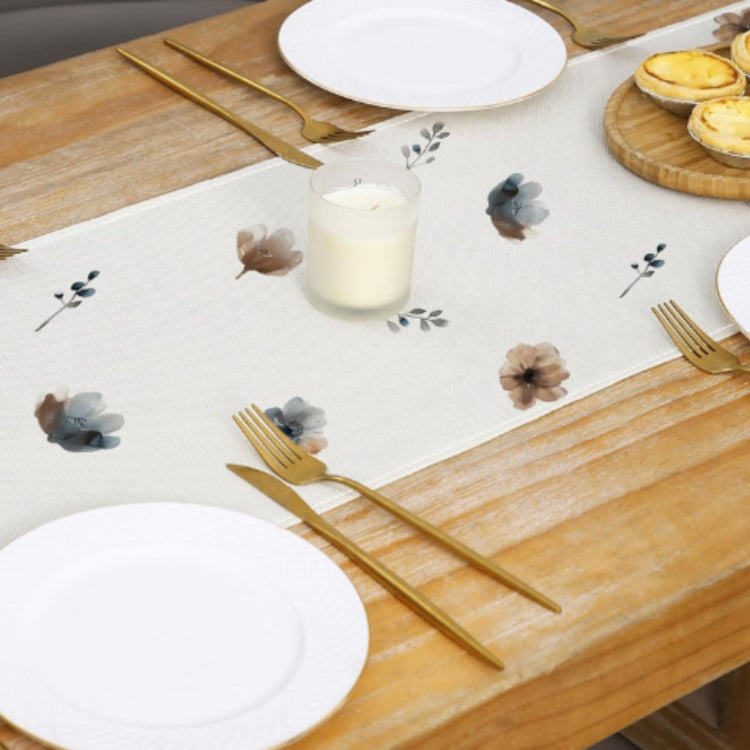 Overhead view of small floral motifs along the centre of a cream table runner.