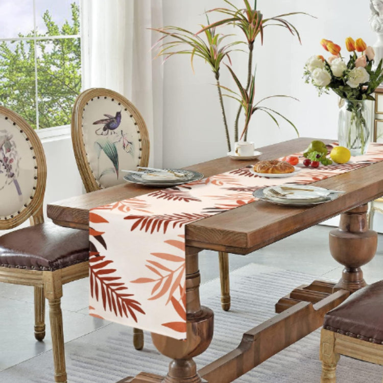 White table runner with rust-coloured leaf silhouettes.