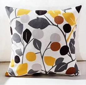White cushion cover with grey and black leaves and yellow and brown circular flowers.