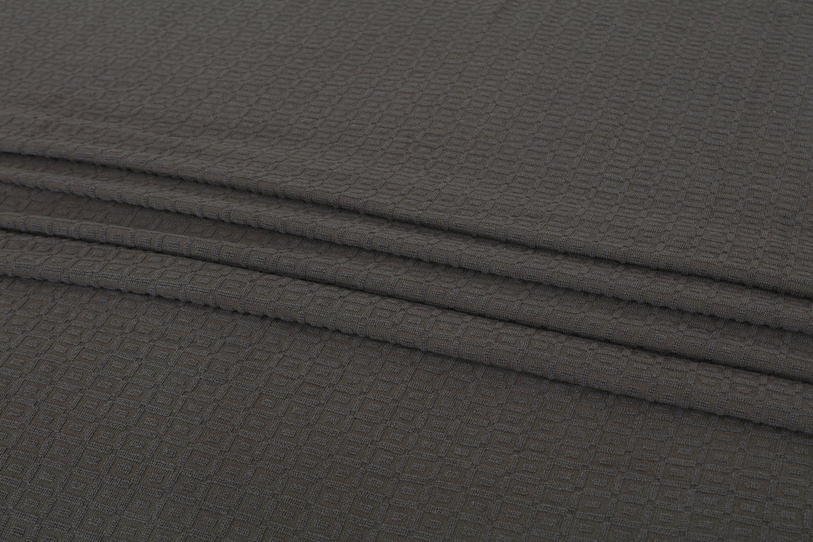 Close-up of the texture and folds of a charcoal grey cotton thermal blanket.