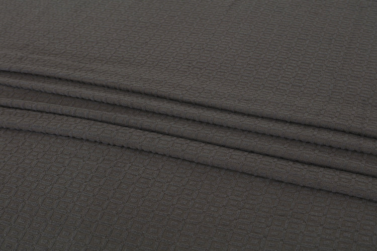 Close-up of the texture and folds of a charcoal grey cotton thermal blanket.