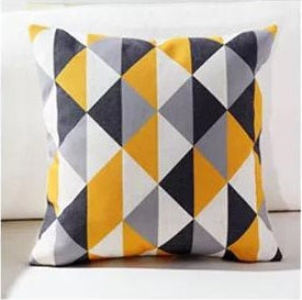 Cushion cover with yellow, grey, black and white geometric diamonds.