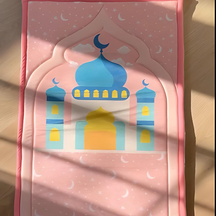 Pink children's prayer mat with a blue-domed mosque illustration.