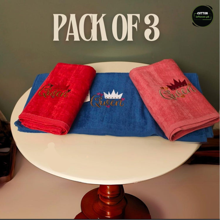 Three colourful towels in red, blue and pink with small decorative embroidered motifs.
