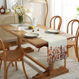 Cream table runner with orange and green tropical botanical motifs at its end.