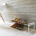 Low white shoe rack with wood-tone rails holding shoes