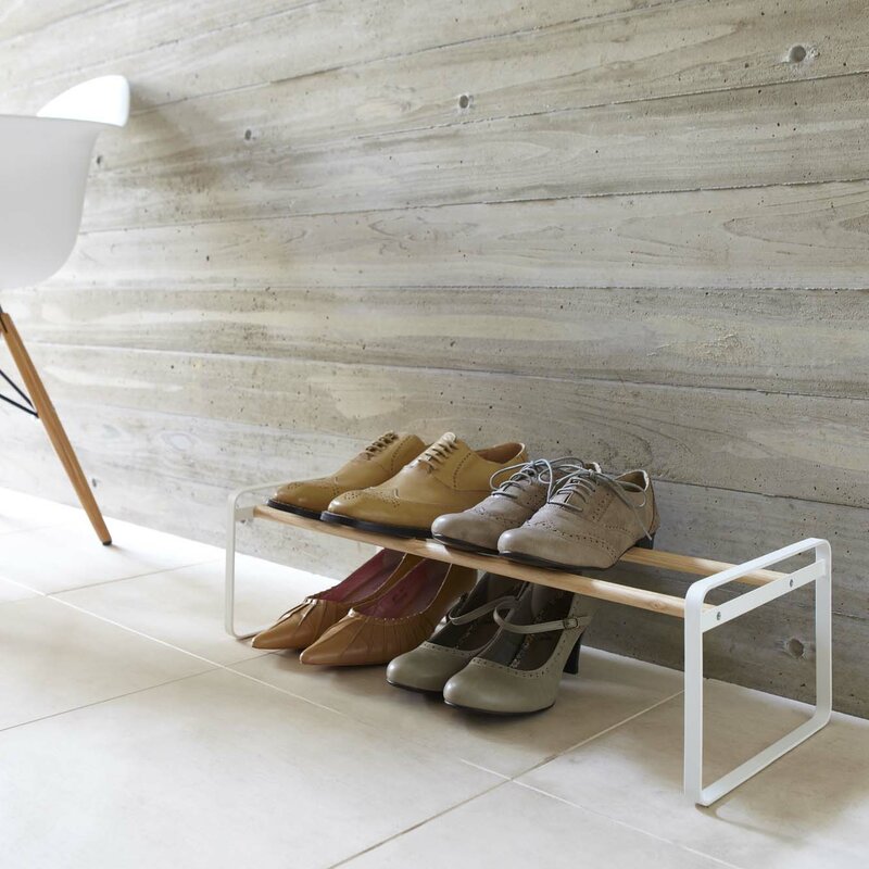 Low white shoe rack with wood-tone rails holding shoes