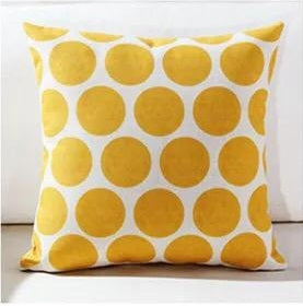 White cushion cover with large yellow polka dots.
