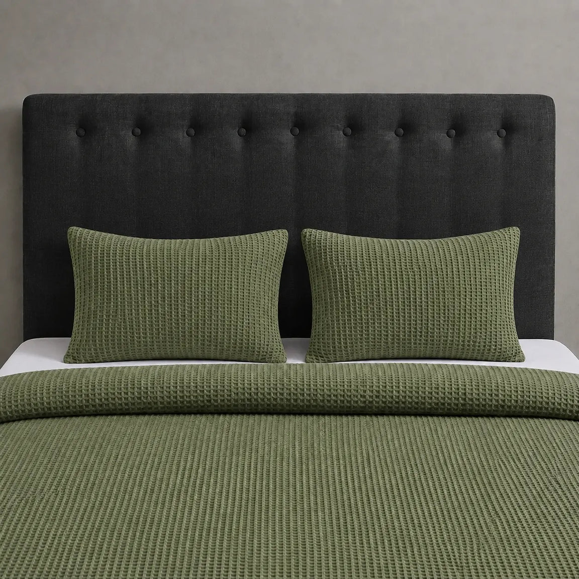Olive green waffle-weave blanket and matching pillow covers on a bed.