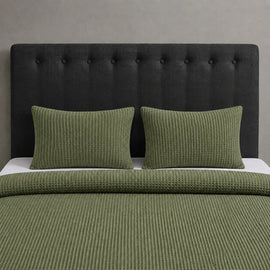 Olive green waffle-weave blanket and matching pillow covers on a bed.