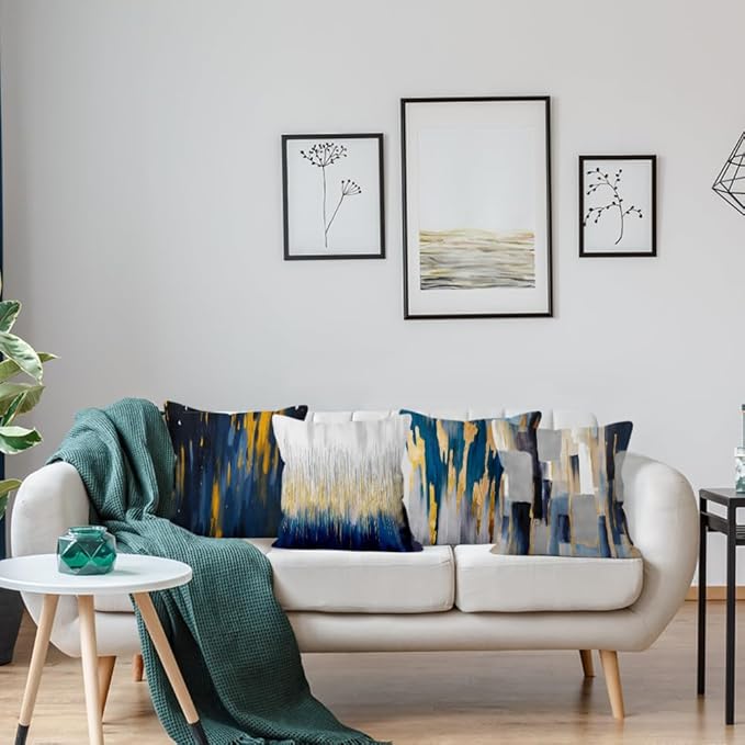 Navy, grey and gold coloured abstract cushion covers arranged on a sofa.