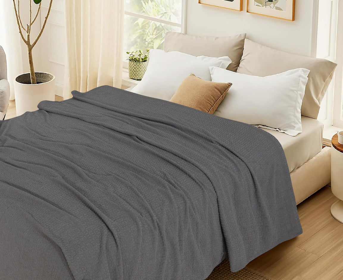 Charcoal grey cotton thermal blanket spread across a bed.