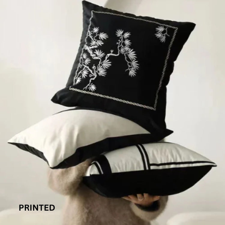Stack of black and cream cushion covers showing floral and geometric printed designs.