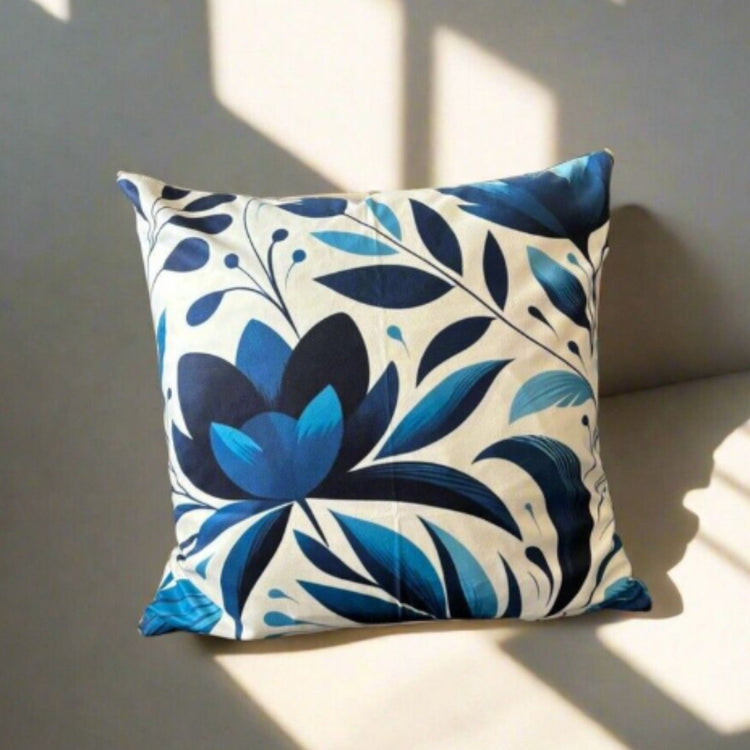Cream cushion cover with a large blue flower and sweeping blue leaves.