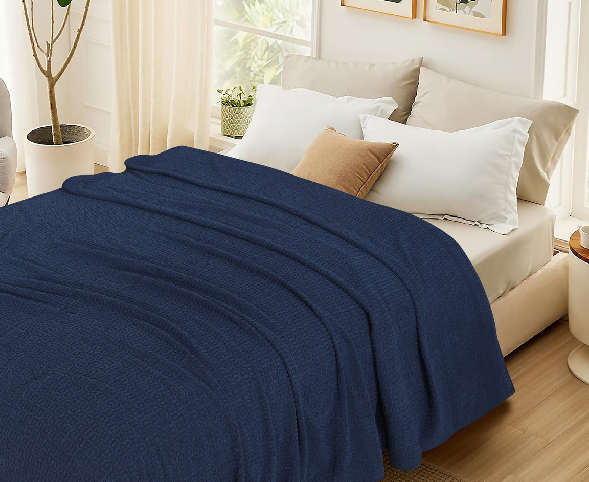Navy cotton thermal blanket spread across a bed.
