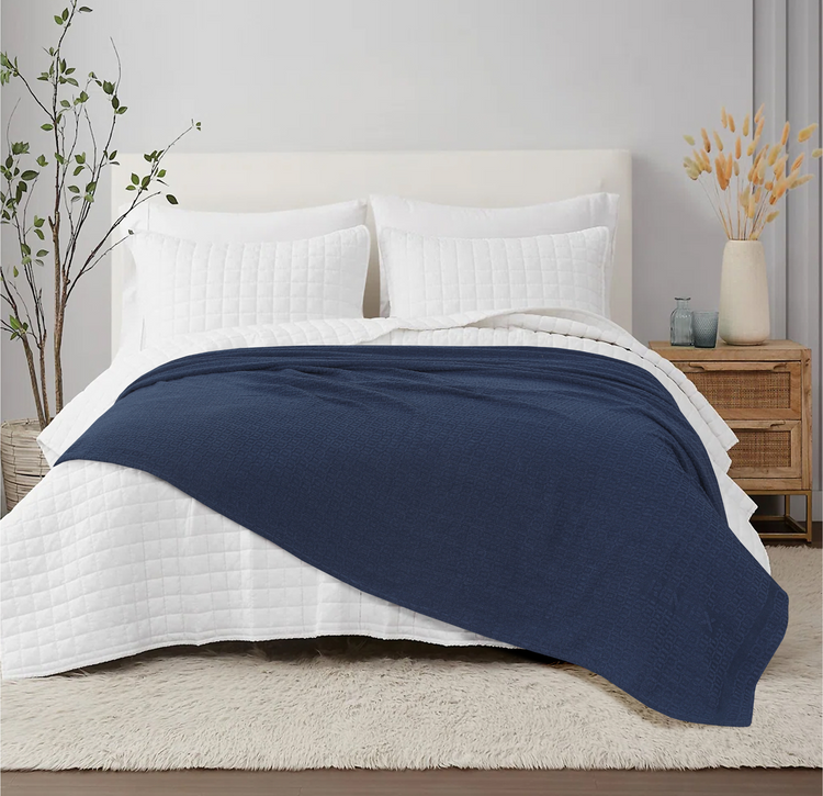 Navy cotton thermal blanket spread across a bed.