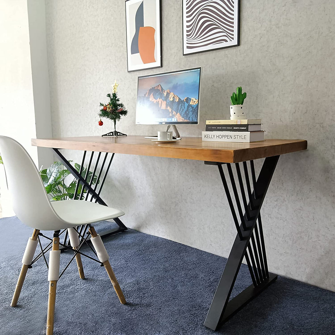 Brown-top desk with black crossed leg supports holding a computer beside a white chair.
