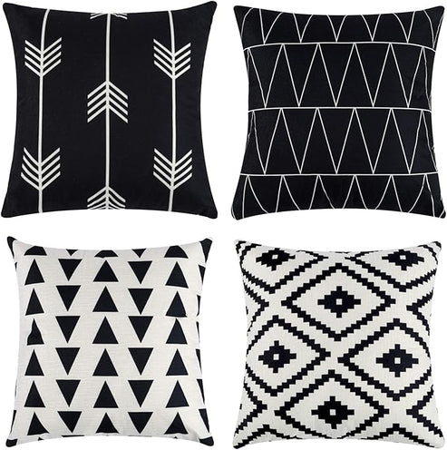 Four black and white cushion covers with arrows, triangles and stepped diamond patterns.
