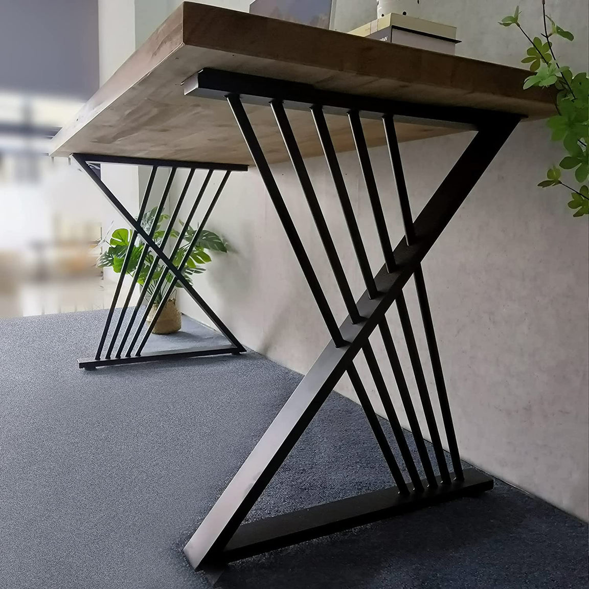 Close-up of a desk black crossed-leg support with narrow diagonal rods beneath a brown top.