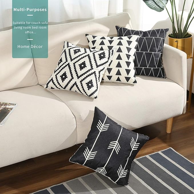 Four black and white geometric cushion covers displayed on a sofa and rug.