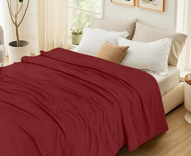 Burgundy cotton thermal blanket spread across a bed.