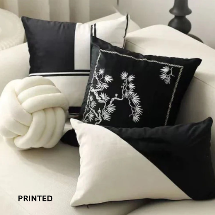 Close view of black and cream printed cushion covers beside a cream knot cushion.
